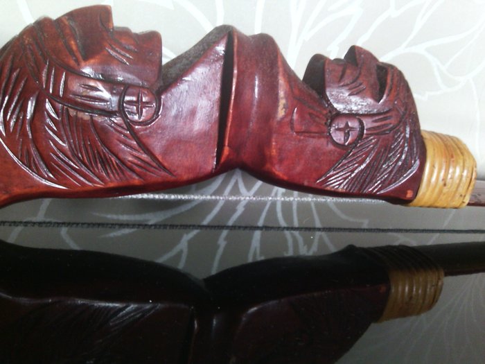 Bow made of carved wood with two Indian heads