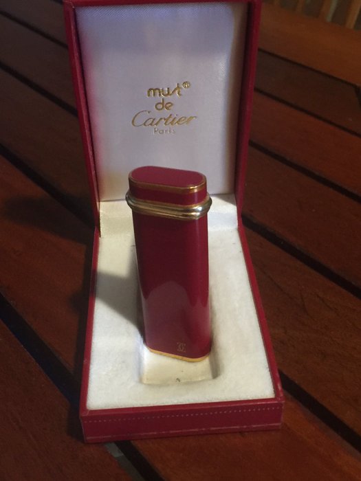 Must de CARTIER : Lighter in red lacquer, three golds, model Trinity in lacquered metal, in its case. Very good condition.