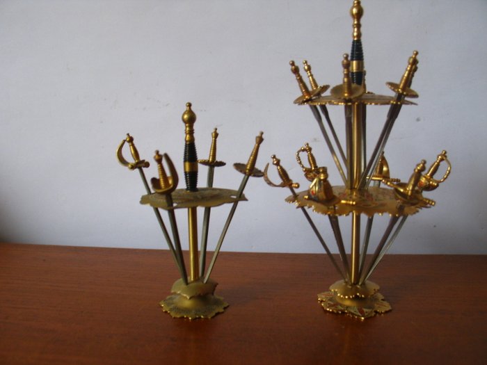 Two stands with 16 vintage Toledo cocktail sticks shaped like swords.