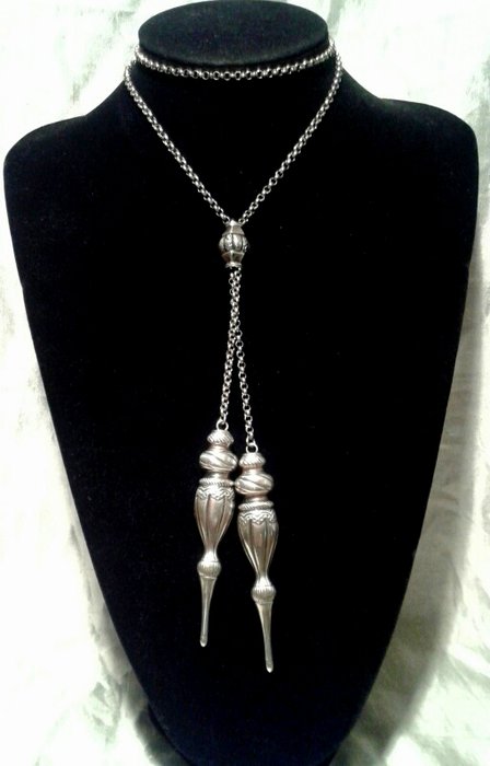 Silver jasseron necklace with two knitting needle tops.
