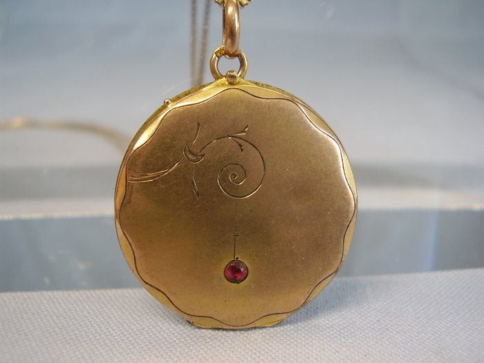 Antique gold medallion opening pendant in rose gold with round faceted ruby on necklace
