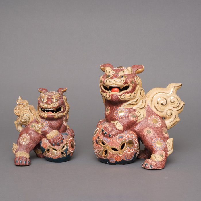 Nice pair of Kutani'ware porcelain figures of temple lions protecting a rich decorated ball. - Keramiek, Porselein - Japan
