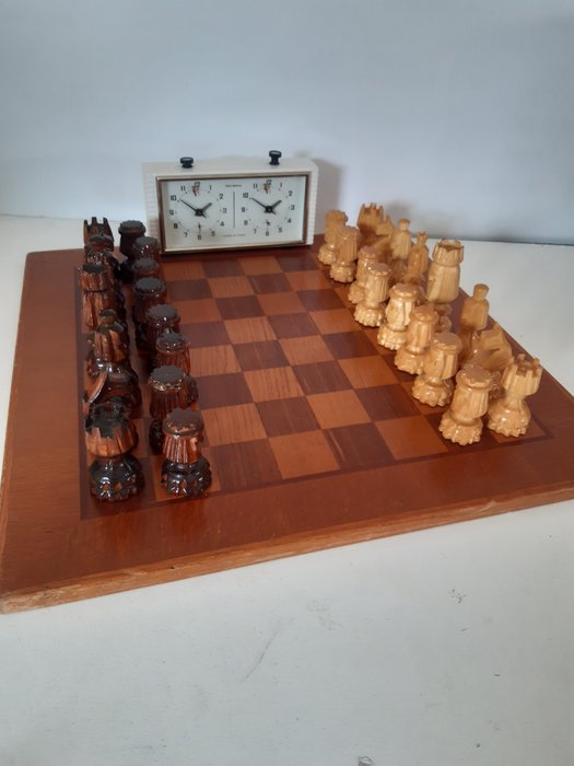 Relógio de xadrez antigo no tabuleiro de xadrez com figuras