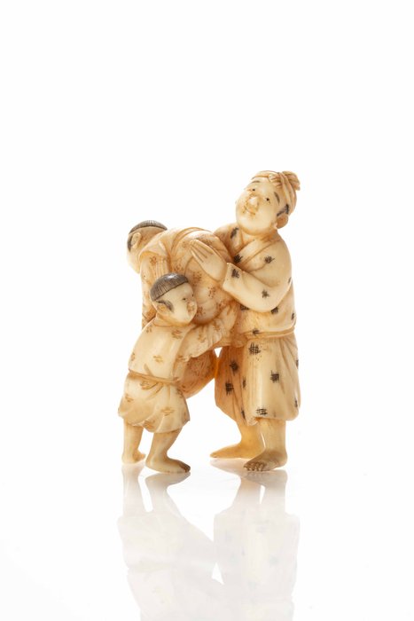 Un netsuke-okimono de marfil que representa a dos niños y un hombre jugando. - Marfil - Japón - Período Meiji (siglo XIX)